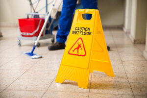 Wet floor sign and professional janitorial company cleaning staff mopping